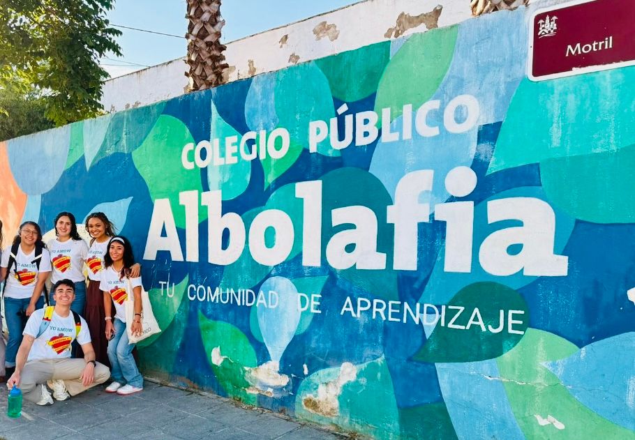 group of people standing in front of mural