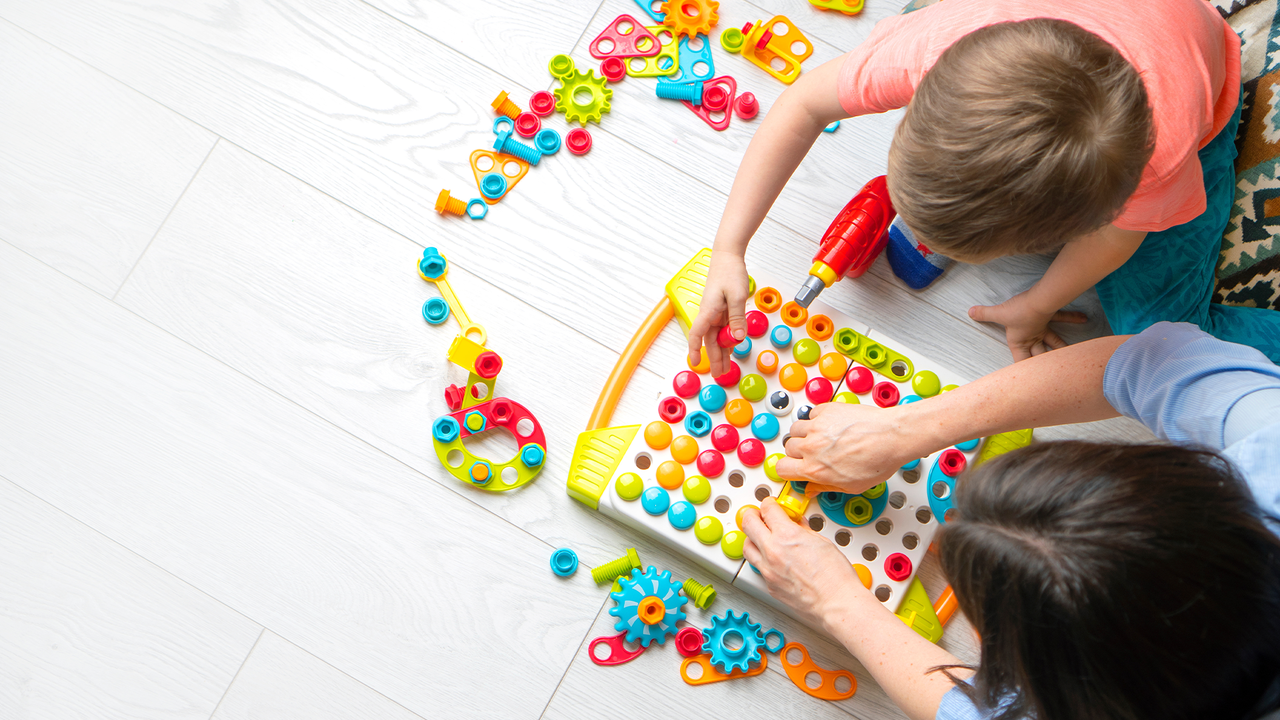 photo of child and adult playing with toys on floor