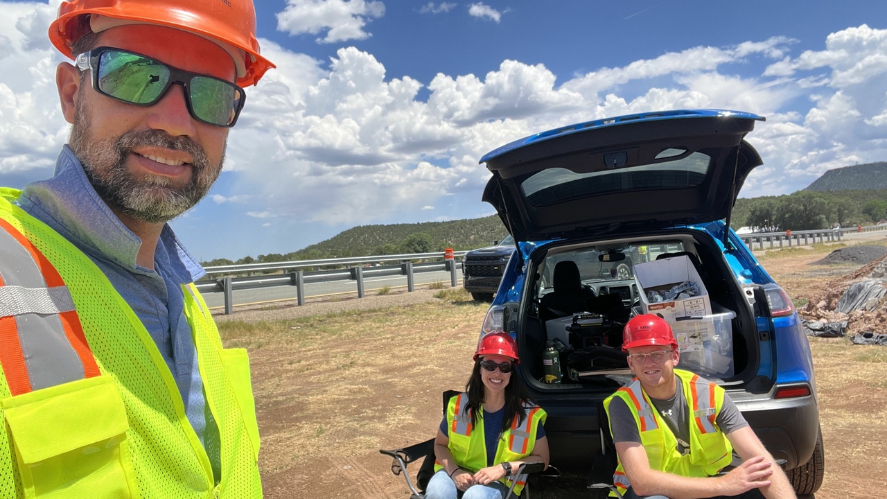 Photo of Fabiano Amorim and two other adults wearing safety vests and helmets outdoors