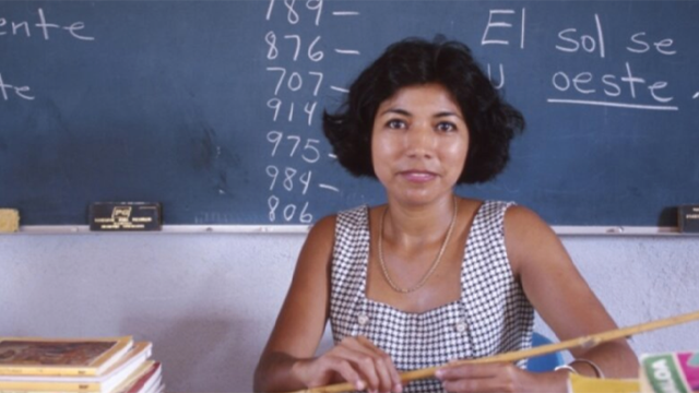 photo of woman sitting in front of chalkboard with spanish writing