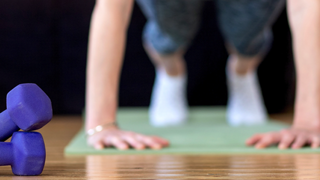 photo of an adult doing a pushup next to small weights