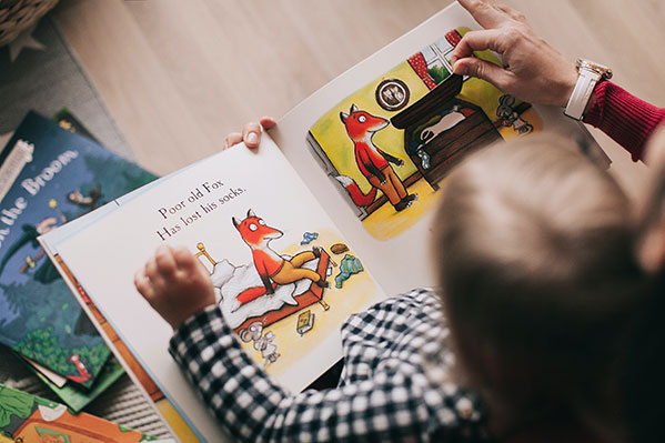 Very young child holding a book open to a page with illustrations of a fox